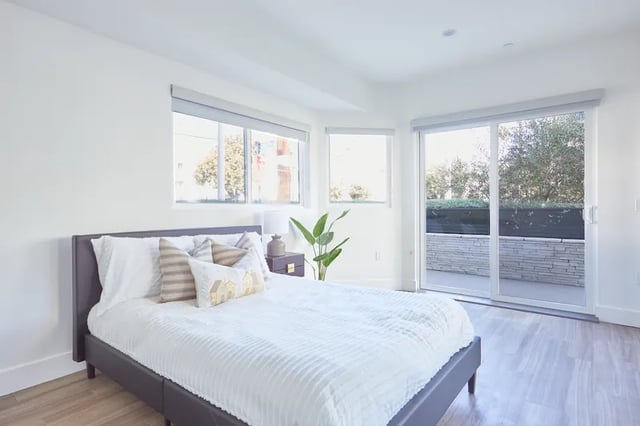 Bed with decorative pillows nightstand plant patio door bedroom at 1025 Berendo Villas in Los Angeles Student Accommodation