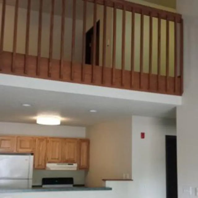 Wooden railing loft over kitchen and refrigerator Kitchen at Biondo Properties, LLC in La Crosse Student Accommodation
