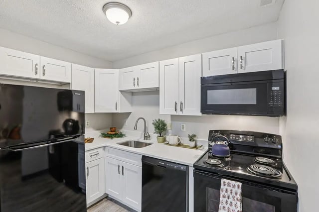 Black refrigerator white cabinets sink and stove kitchen at Beacon Hill Apartments in Muncie Student Accommodation