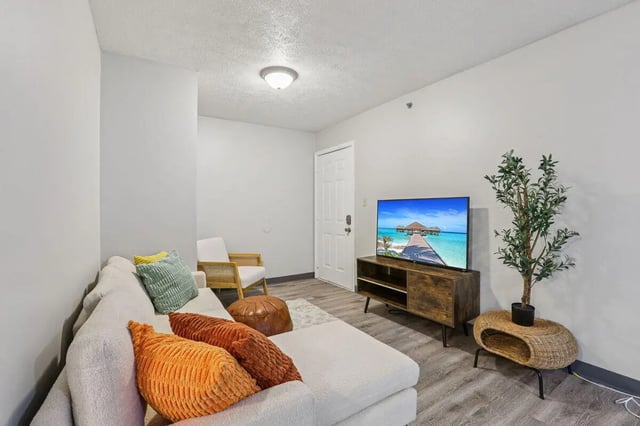 White sectional sofa with colorful pillows and TV living room at Beacon Hill Apartments in Muncie Student Accommodation