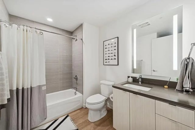 Modern bathroom with tub toilet sink and mirror. at Alta Peak in Portland Student Accommodation