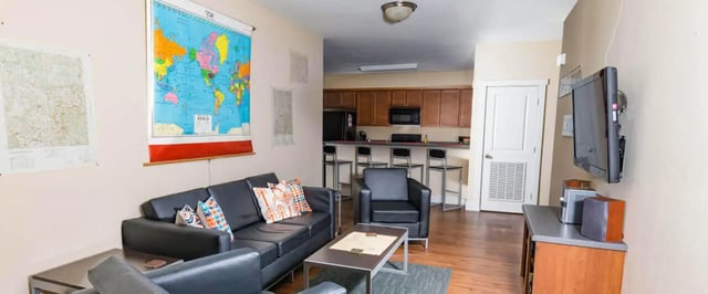 Black couches chair world map TV kitchen area living room at Beacon Springfield in Springfield Student Accommodation