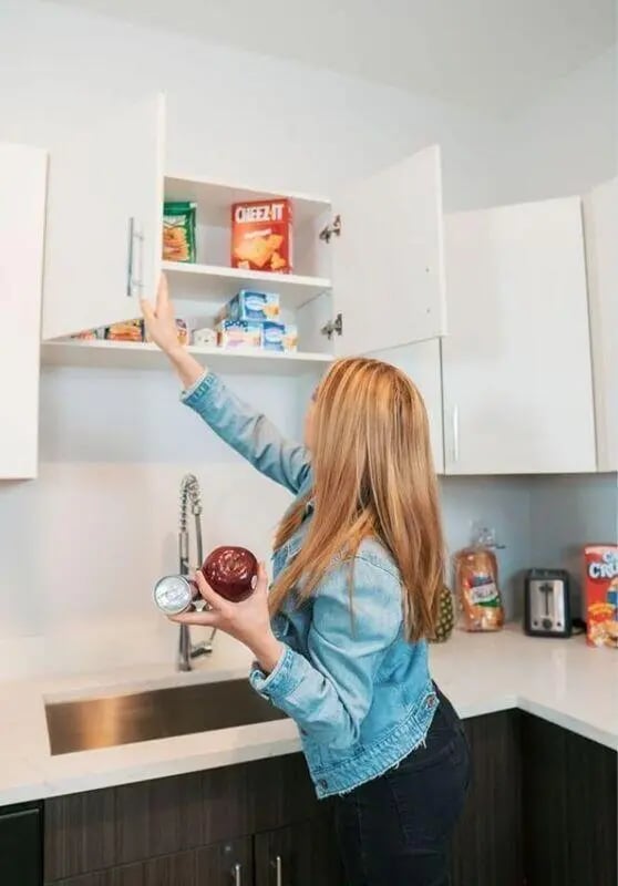 Woman reaching into cabinet with food kitchen counter Kitchen at Advantage Point Student Apartments in Kutztown Student Accommodation