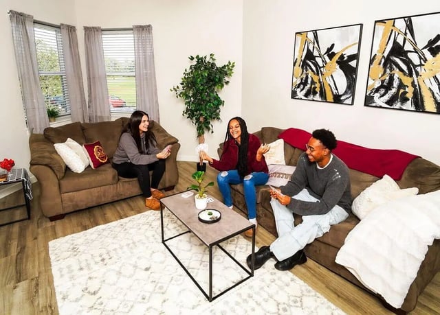 Three friends playing cards on sofas living room at Advantage Point Student Apartments in Kutztown Student Accommodation