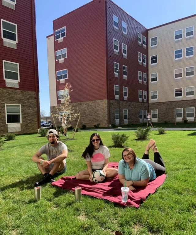 Students relaxing on lawn outside apartments Exterior at Advantage Point Student Apartments in Kutztown Student Accommodation