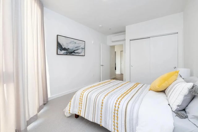 Bed with yellow pillows artwork and closet bedroom at 11 East Pleasant in Amherst Student Accommodation