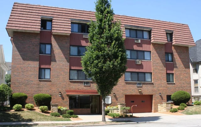Brick building with green trees and garage exterior at Campus Court in Milwaukee Student Accommodation