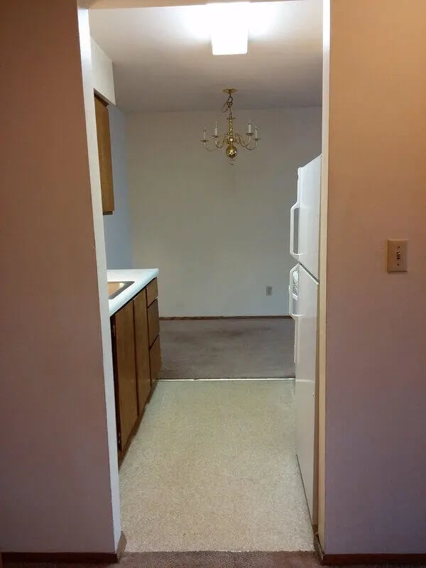Kitchen cabinets refrigerator chandelier dining area living room at Campus Court in Milwaukee Student Accommodation
