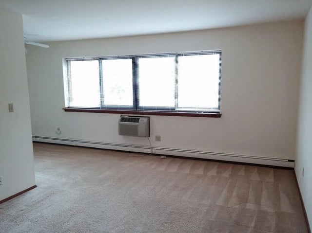 Carpeted room with large window and AC living room at Campus Court in Milwaukee Student Accommodation