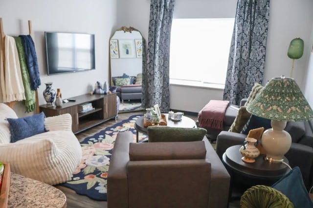 Chairs couch TV and floral rug living room at Bear Village Apartments in Springfield Student Accommodation