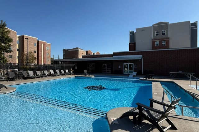 Pool with lounge chairs and apartment buildings exterior at Bear Village Apartments in Springfield Student Accommodation