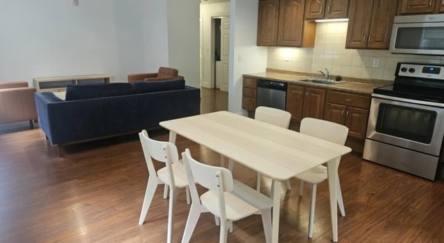 Dining table and chairs with kitchen living room at Clyde Street Apartments in Pittsburgh Student Accommodation