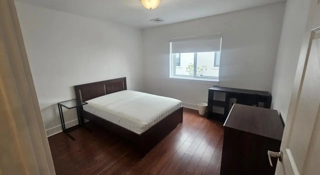 Dark wood bed white mattress glass side table bedroom at Clyde Street Apartments in Pittsburgh Student Accommodation
