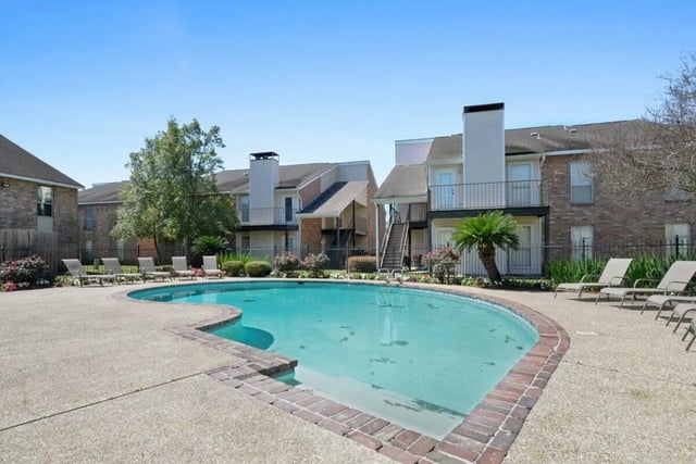 Swimming pool with lounge chairs and apartment buildings exterior at Beau Chene Condominiums, Inc in Baton Rouge Student Accommodation