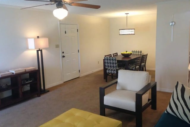 Living room with dining area and white armchair Living Room at Beau Chene Condominiums, Inc in Baton Rouge Student Accommodation