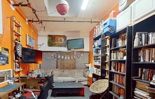 Sofa shelves desk and dartboard living room at Artist Housing in Los Angeles Student Accommodation