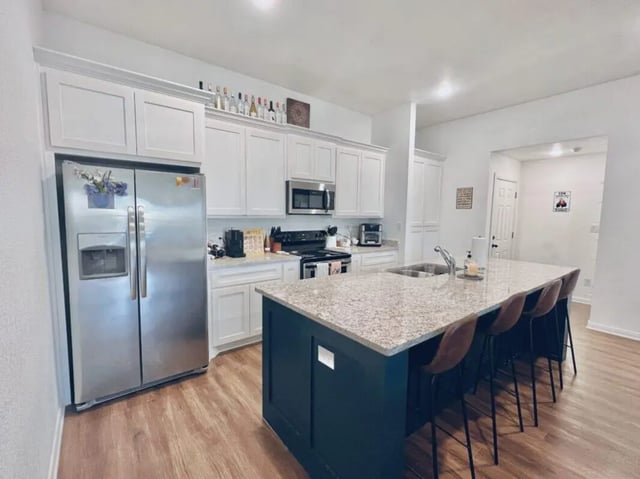 Stainless steel refrigerator white cabinets granite island kitchen at Black Bear Village in Waco Student Accommodation