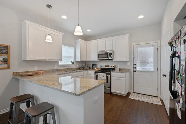 Kitchen with counter stools and appliances kitchen at Black Bear Village in Waco Student Accommodation