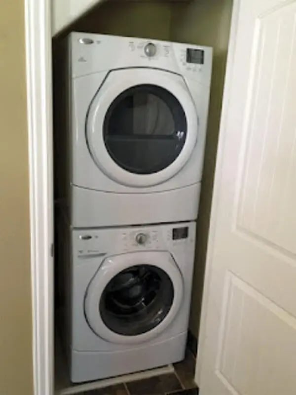 Stacked white washing machine and dryer Laundry room at City Creek Manor in Salt Lake City Student Accommodation