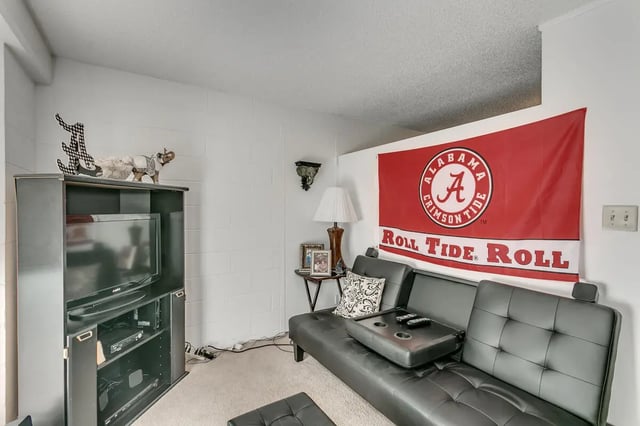 Black sofa Alabama flag TV stand living room at Cobblestone Court Apartments in Tuscaloosa Student Accommodation