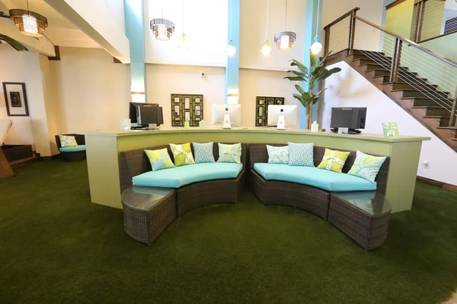 Curved wicker sofas with turquoise cushions and decorative pillows reception area at Collegiate Communities in West Lafayette Student Accommodation