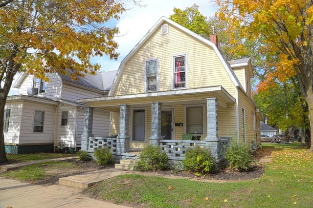 Yellow house porch with stone columns exterior at Collegiate Communities in West Lafayette Student Accommodation
