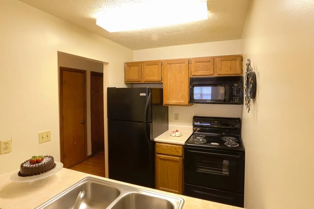Black refrigerator microwave range cabinets cake kitchen at Collegiate Communities in West Lafayette Student Accommodation