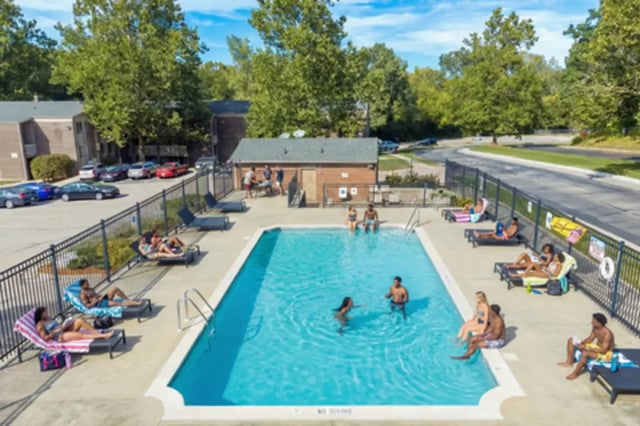 People relaxing by pool with lounge chairs and buildings exterior at Campus Hill Apartments in Ithaca Student Accommodation