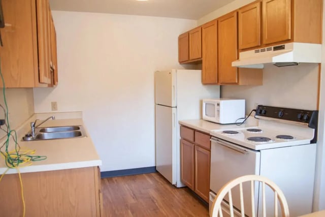Wooden cabinets sink stove microwave and refrigerator kitchen at Bridgerland Apartments in Logan Student Accommodation