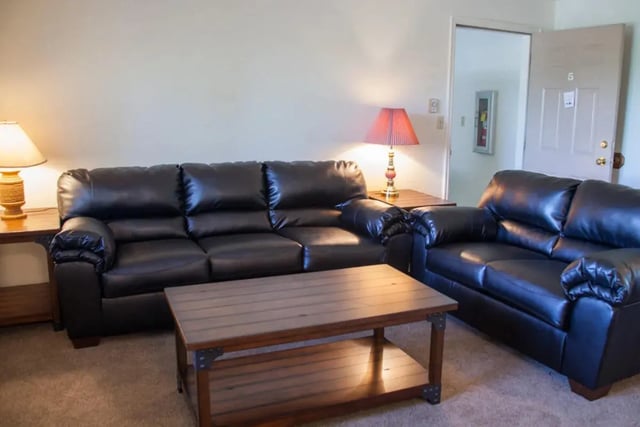 Black leather couches coffee table lamps living room at Bridgerland Apartments in Logan Student Accommodation