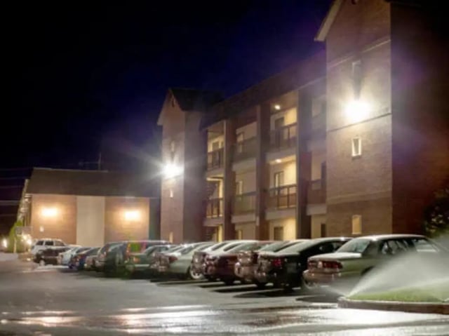 Cars parked outside brick building at night exterior at Bridgerland Apartments in Logan Student Accommodation