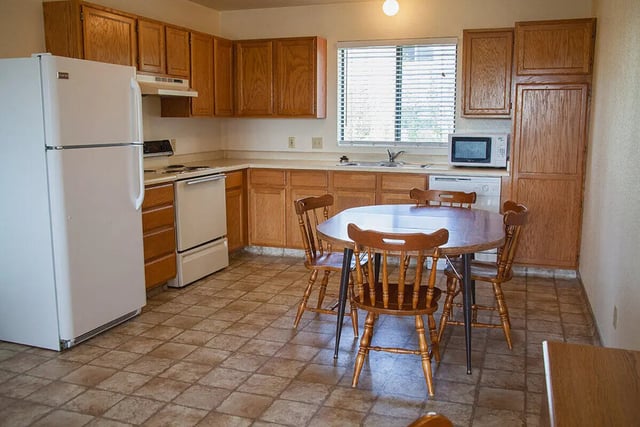Refrigerator stove table chairs cabinets kitchen at Bridgerland Apartments in Logan Student Accommodation