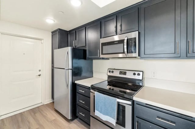 Stainless steel refrigerator dark cabinets microwave oven stove kitchen at Ascent at Campus of Life in San Diego Student Accommodation