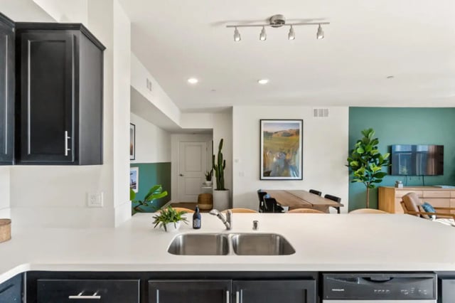 Kitchen island sink dark cabinets dining area living room kitchen at Ascent at Campus of Life in San Diego Student Accommodation