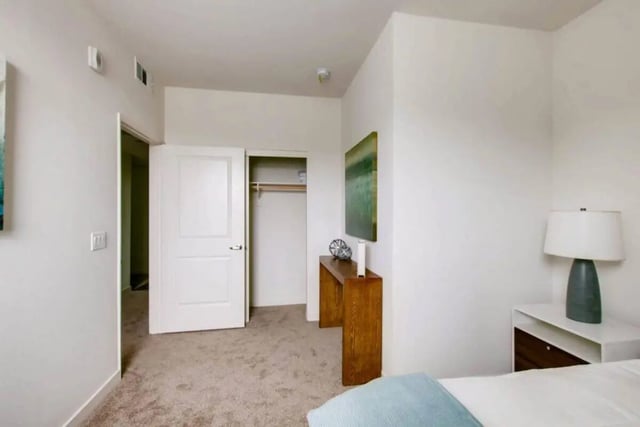 Closet open doors bedside table lamp painting Bedroom at Ascent at Campus of Life in San Diego Student Accommodation