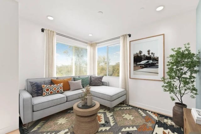 Gray sectional sofa patterned rug wooden table artwork living room at Ascent at Campus of Life in San Diego Student Accommodation