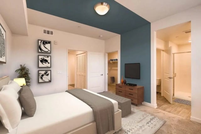 Bed with artwork TV dresser and bathroom bedroom at Ascent at Campus of Life in San Diego Student Accommodation