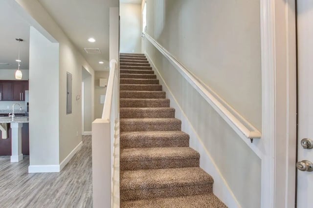 Carpeted stairs white railing hallway kitchen entrance Stairway at Ashburn Hills Townhomes in Tallahassee Student Accommodation