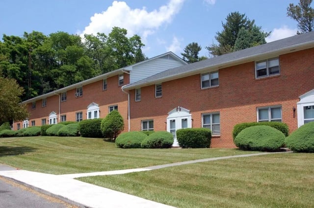 Red brick apartment building with manicured lawns exterior at Collegiate Court in Blacksburg Student Accommodation