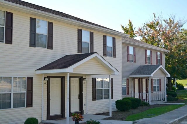 Apartment building with beige siding and dark shutters exterior at Collegiate Court in Blacksburg Student Accommodation