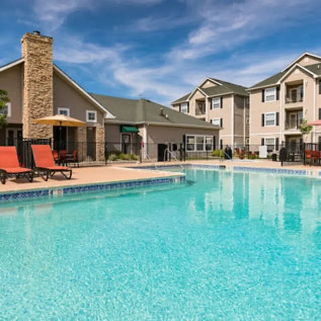 Pool with lounge chairs and apartment buildings exterior at Block 36 - Lease by Bed Available in East Lansing Student Accommodation