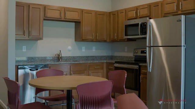 Round table with maroon chairs stainless steel appliances kitchen at Campus Lake Apartments