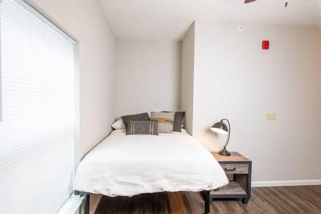 Bed with pillows bedside lamp and blinds bedroom at 120 Flats in West Lafayette Student Accommodation