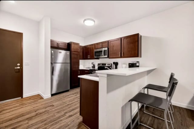 Stainless steel refrigerator dark cabinets two bar stools kitchen at Cedar Flats Apartments in Chico Student Accommodation