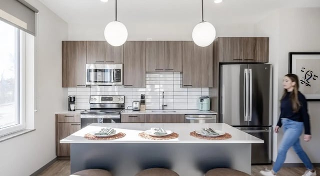 Modern kitchen with island and woman walking kitchen at 525 Linc in Boston Student Accommodation