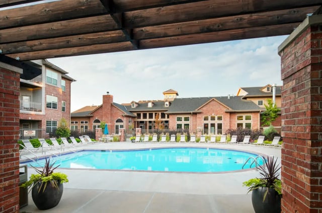 Blue swimming pool with lounge chairs exterior at Broadmoor Hills in Omaha Student Accommodation