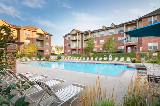 Swimming pool with lounge chairs and apartments exterior at Broadmoor Hills in Omaha Student Accommodation