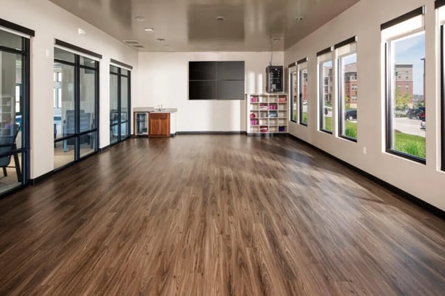 Large empty room with wood floor and TV screen common area at Broadmoor Hills in Omaha Student Accommodation