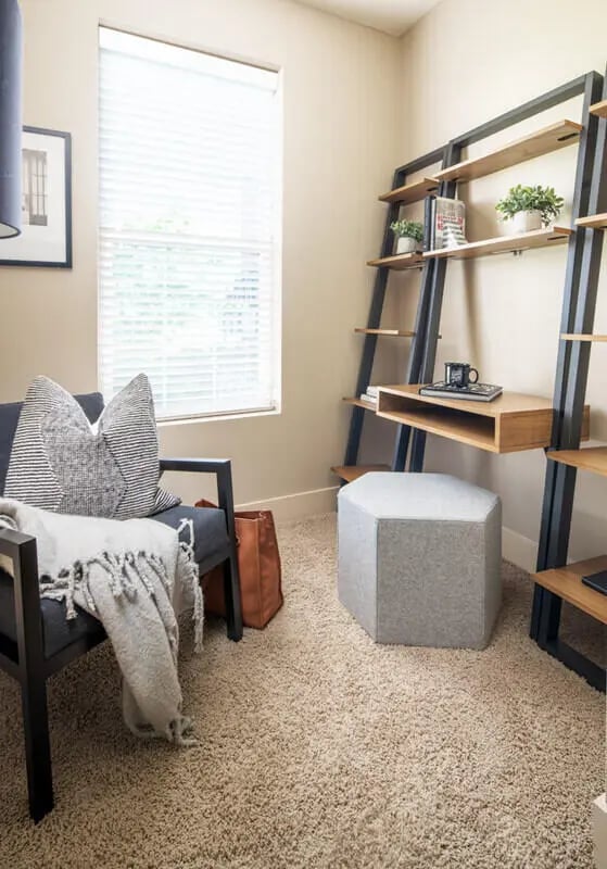 Dark chair striped pillows shelving unit ottoman study area at Broadmoor Hills in Omaha Student Accommodation