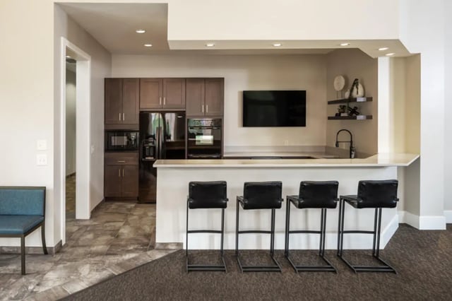 Bar with kitchen cabinets and four stools living room at Broadmoor Hills in Omaha Student Accommodation